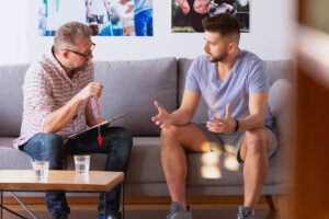 a man and his counselor sit on a couch discussing getting sober and recovery