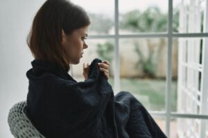 woman sits in a chair looking out a window and thinks to herself about the health effects of morphine vs oxycodone